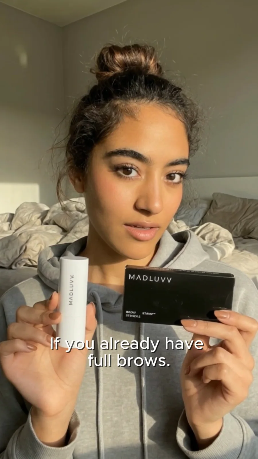 Creator holding the Madluvv brow stamp kit to camera — a frame from the UGC-style video ad